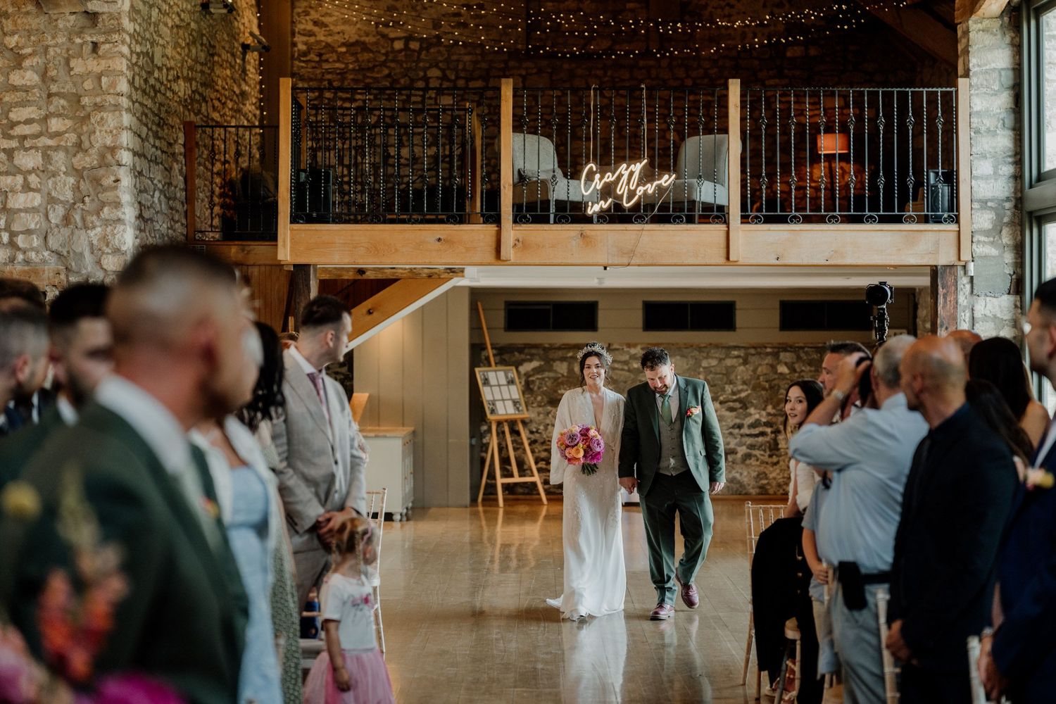 Panoramic view of a wedding reception space with exposed brick walls and twinkling lights at Priston Mill in Bath.