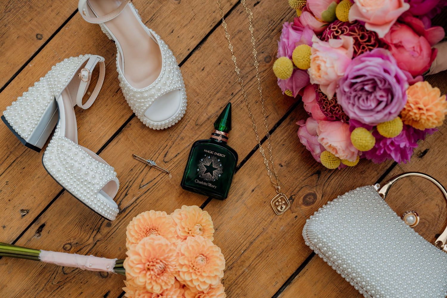 Wedding accessories and floral decorations arranged on wooden floorboards.