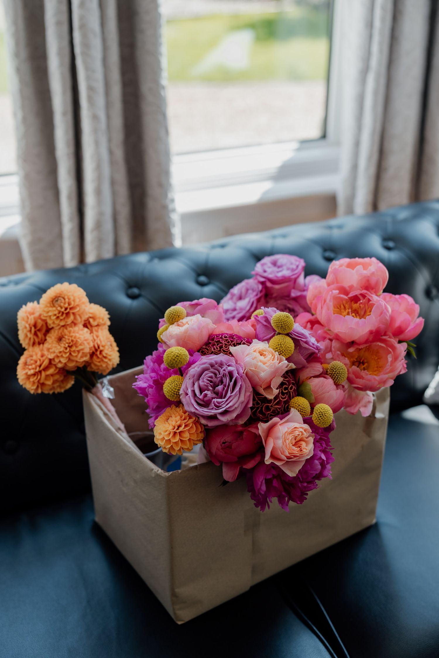 Colorful floral arrangements with pink and orange blooms displayed in white boxes on a blue couch.