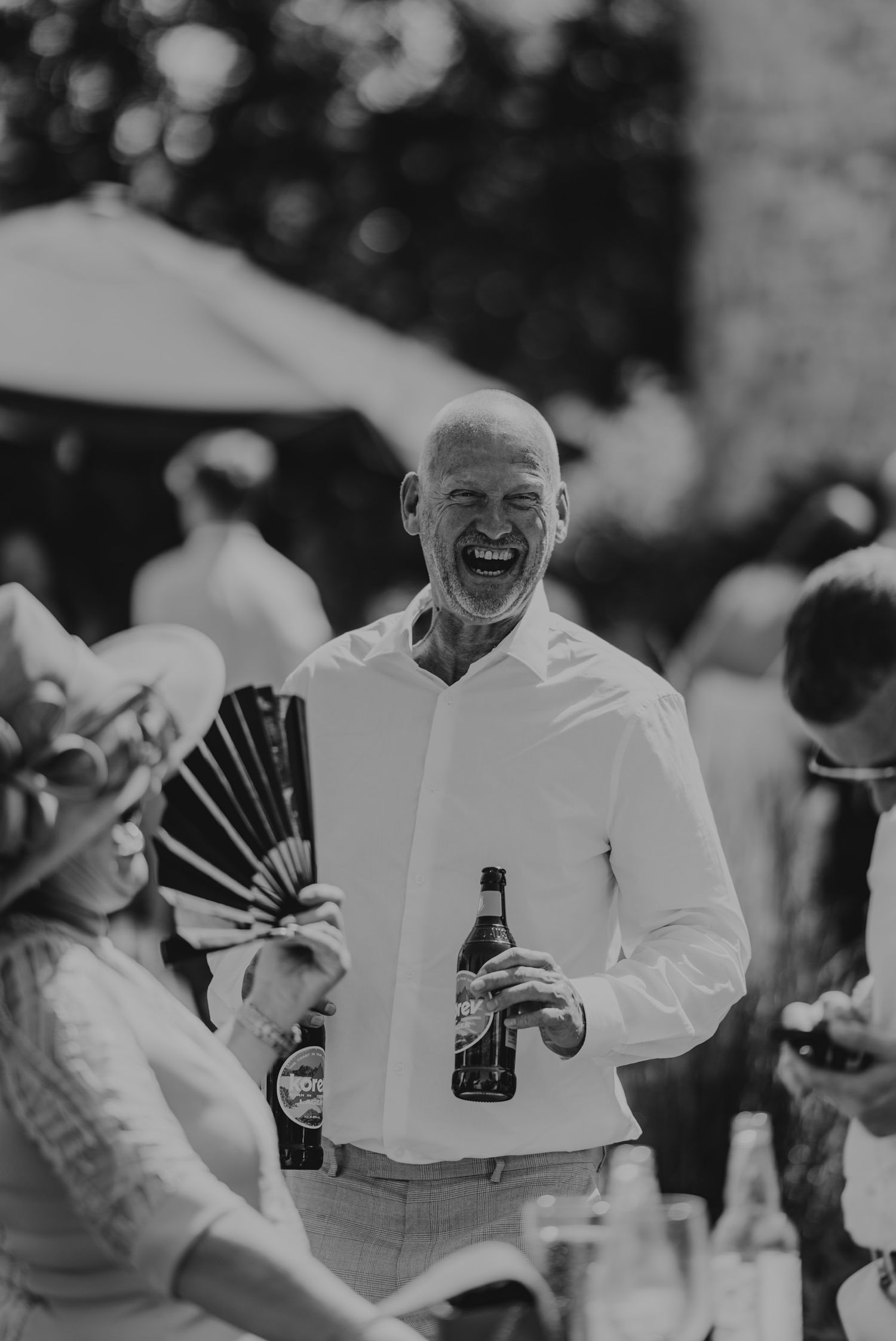 Black and white photo of celebratory outdoor gathering with people holding beverages.