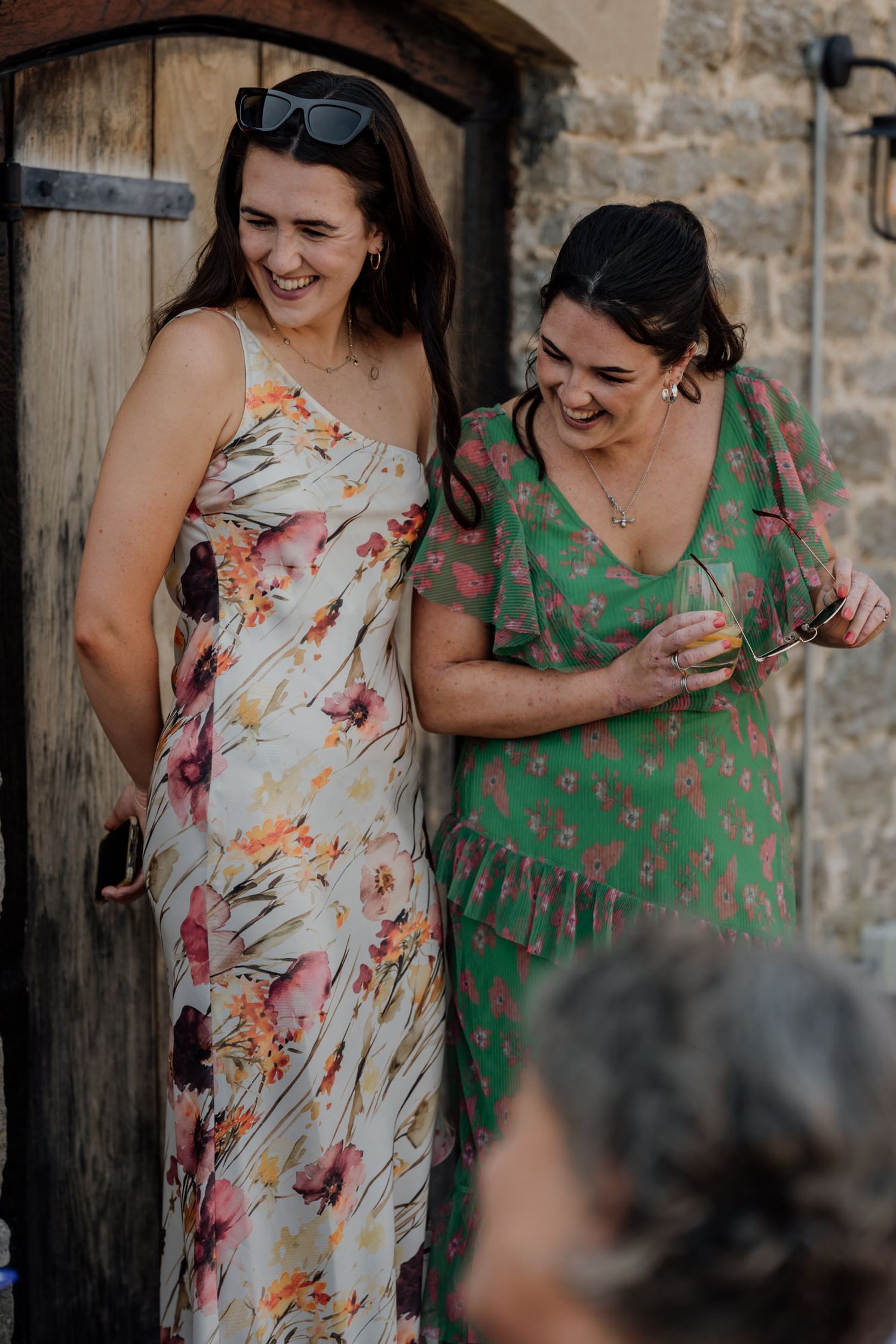 Friends in floral summer dresses celebrate during an outdoor gathering.