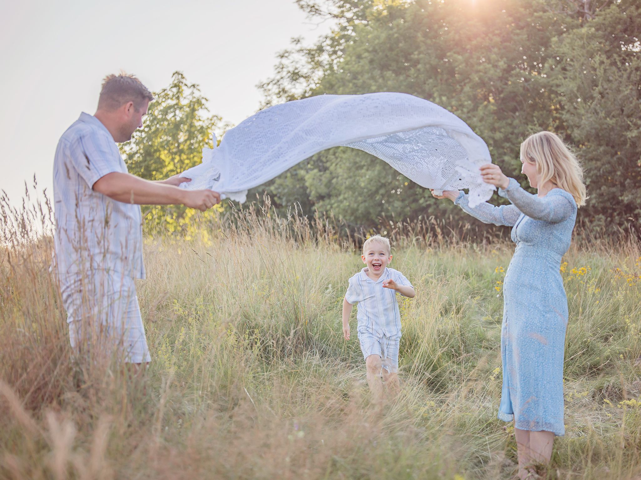 Familj leker i motljus på en äng, familjefotografering i Västerås, MemoriesbyM.se