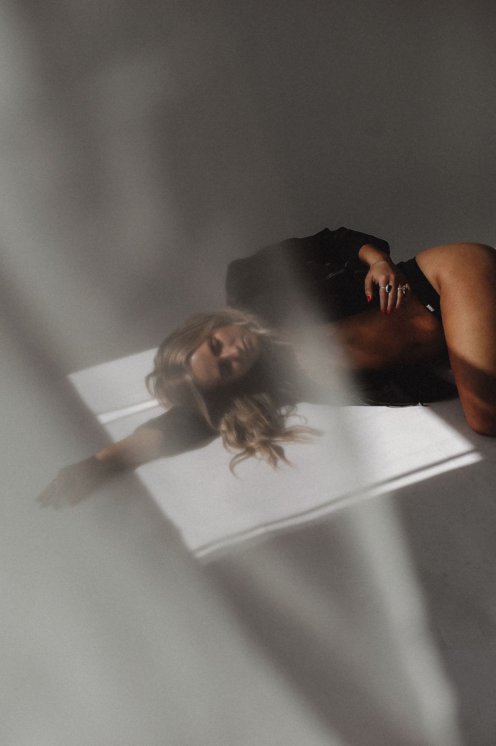 Minimalist boudoir photography with dramatic shadows on white background.