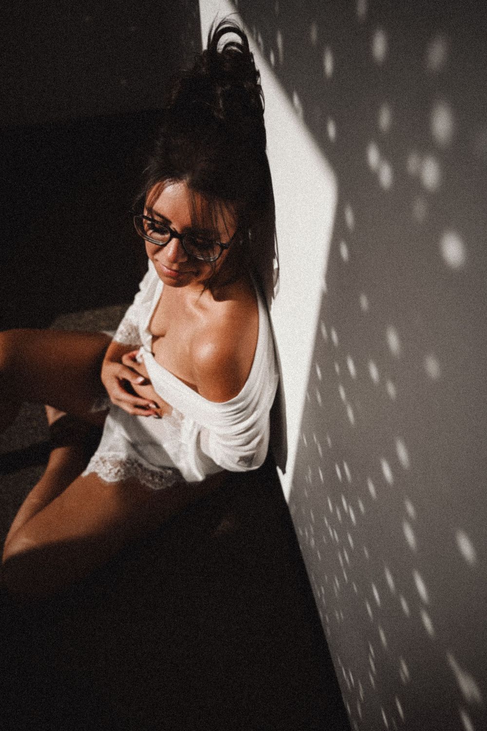Artistic boudoir session with dramatic shadows and soft white lace details.