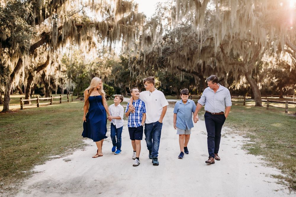 A group of people walking together through a scenic outdoor path with Spanish moss hanging from trees.