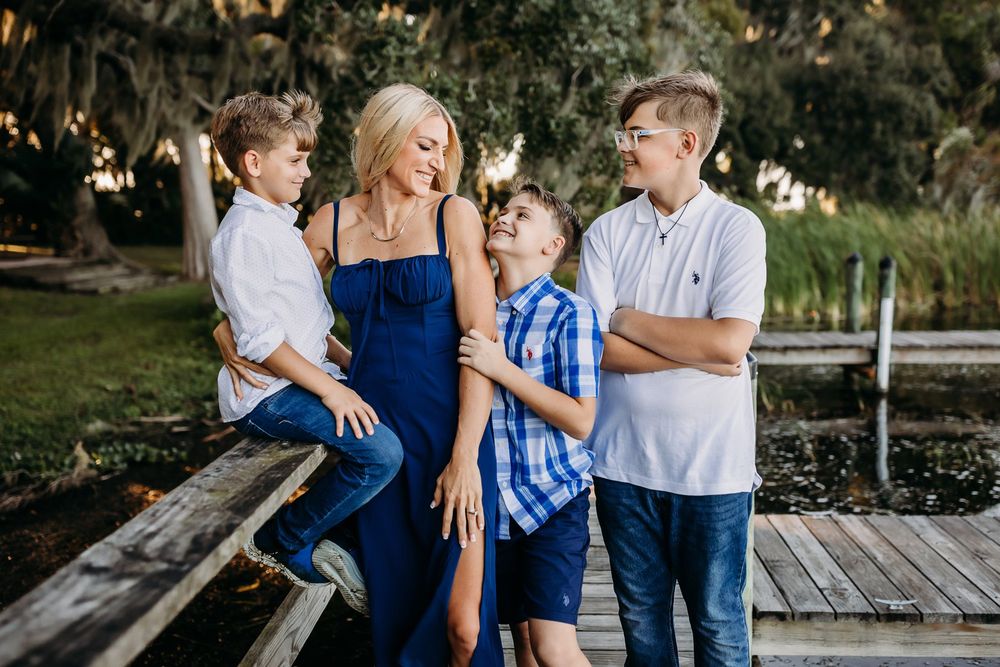 A group wearing coordinated blue and white outfits poses together outdoors during golden hour lighting.