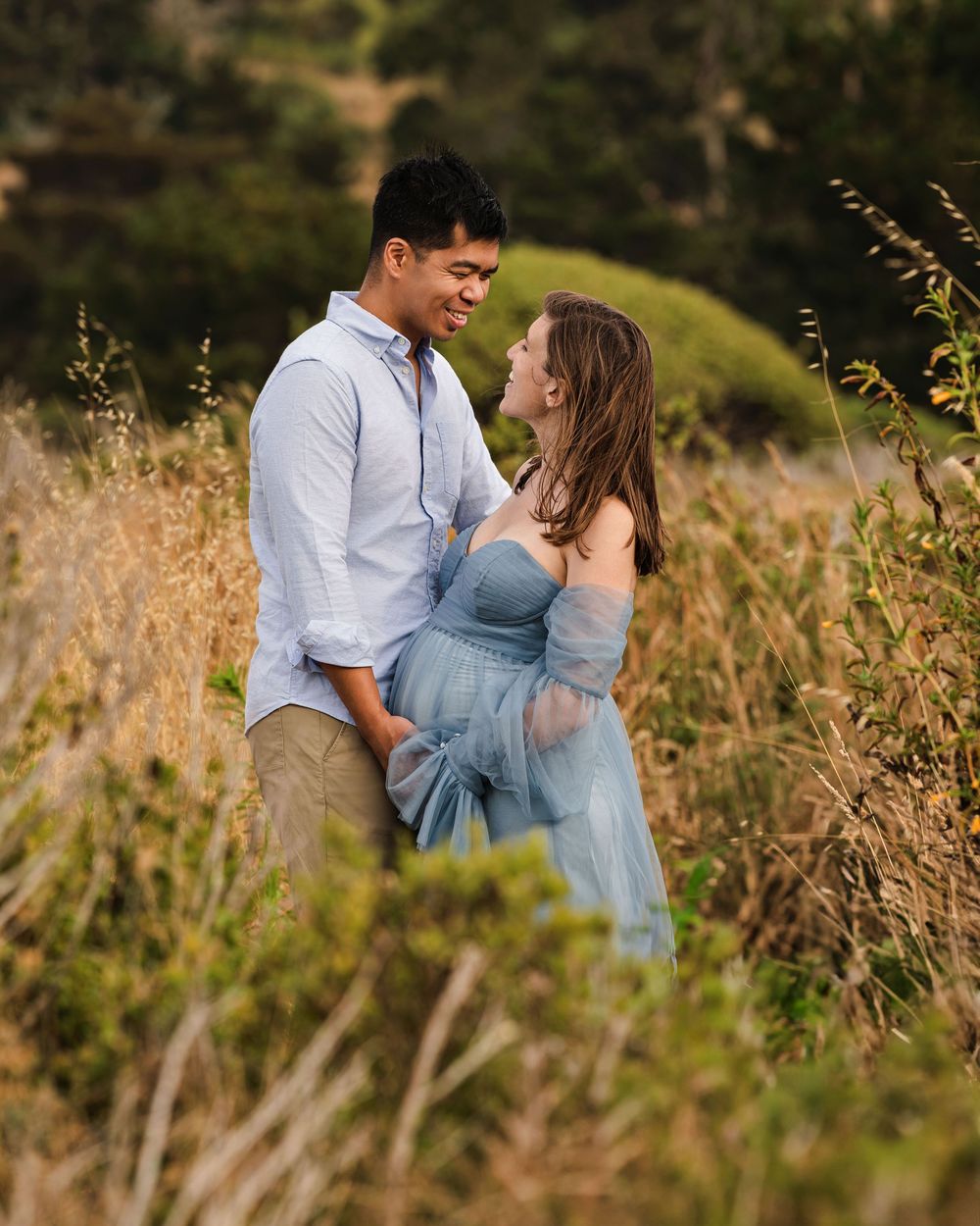Intimate maternity session in tall grass during golden hour.