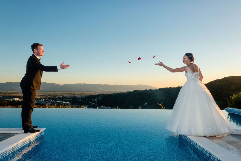 Wedding couple stands silhouetted against dramatic ocean view during sunset.