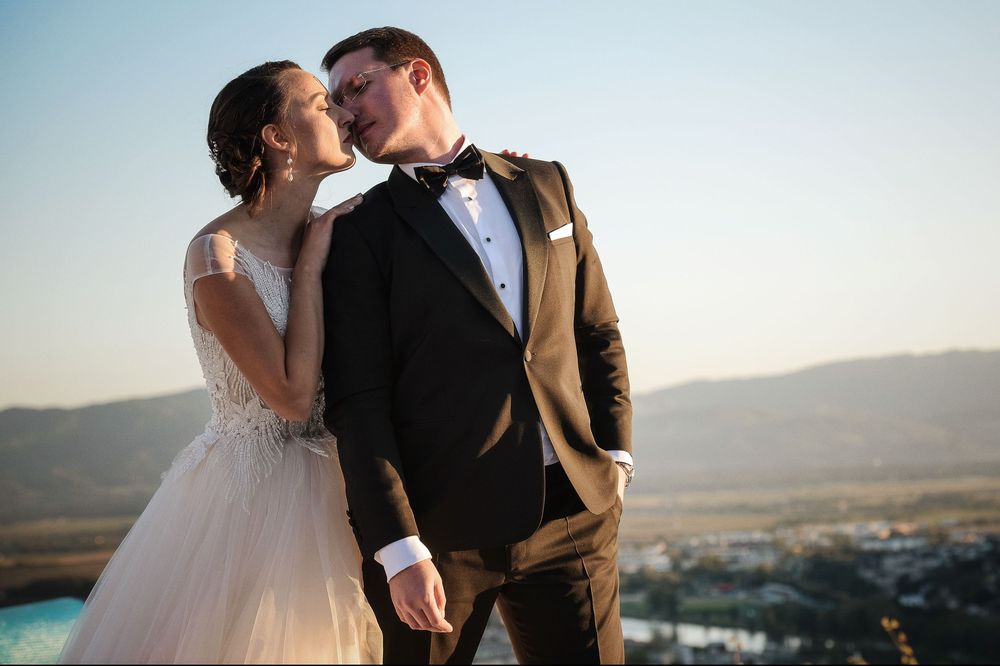 Intimate wedding portraits captured against a scenic mountainous landscape at dusk.