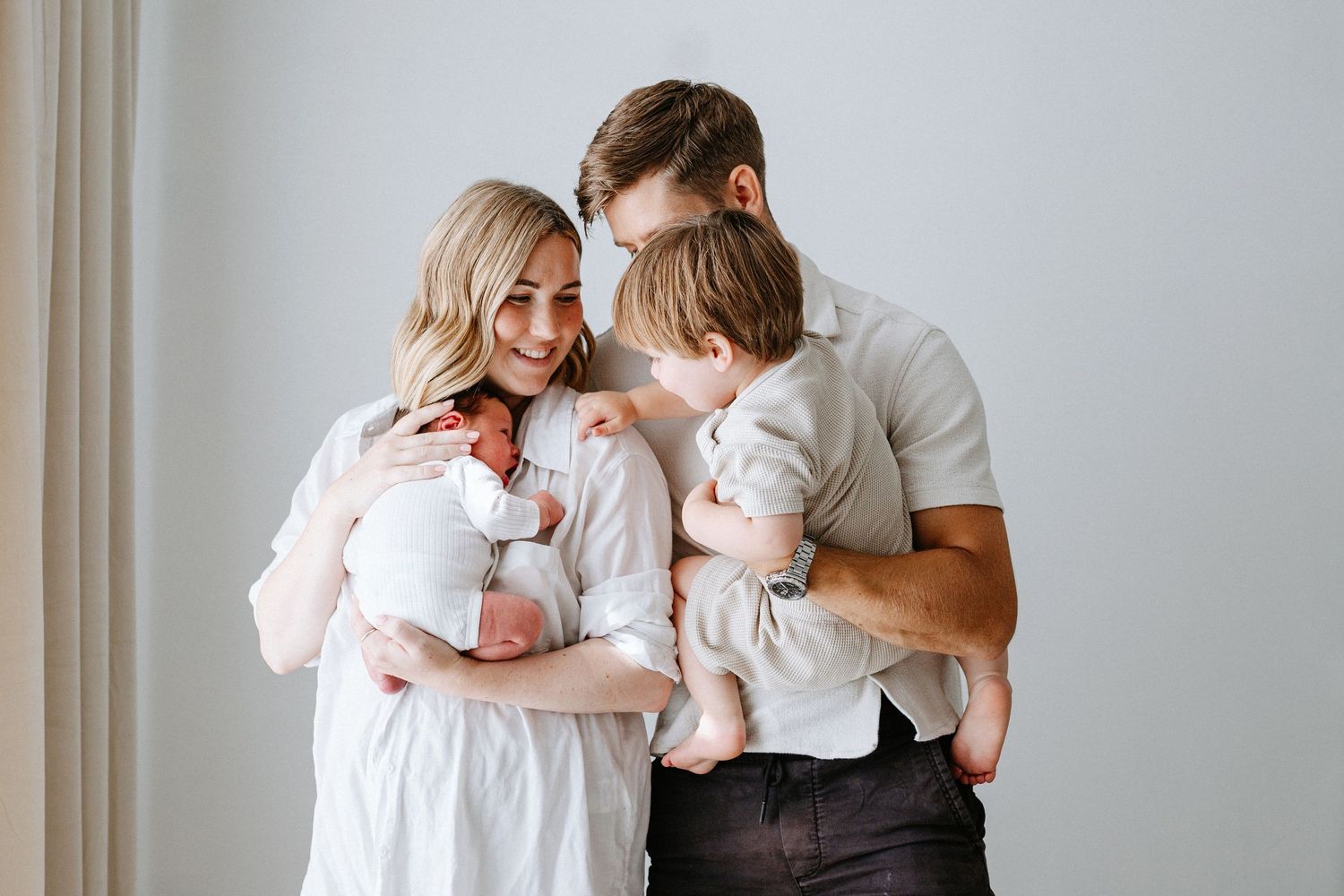Loving collage showing tender family moments in white clothing against a minimalist gray wall.