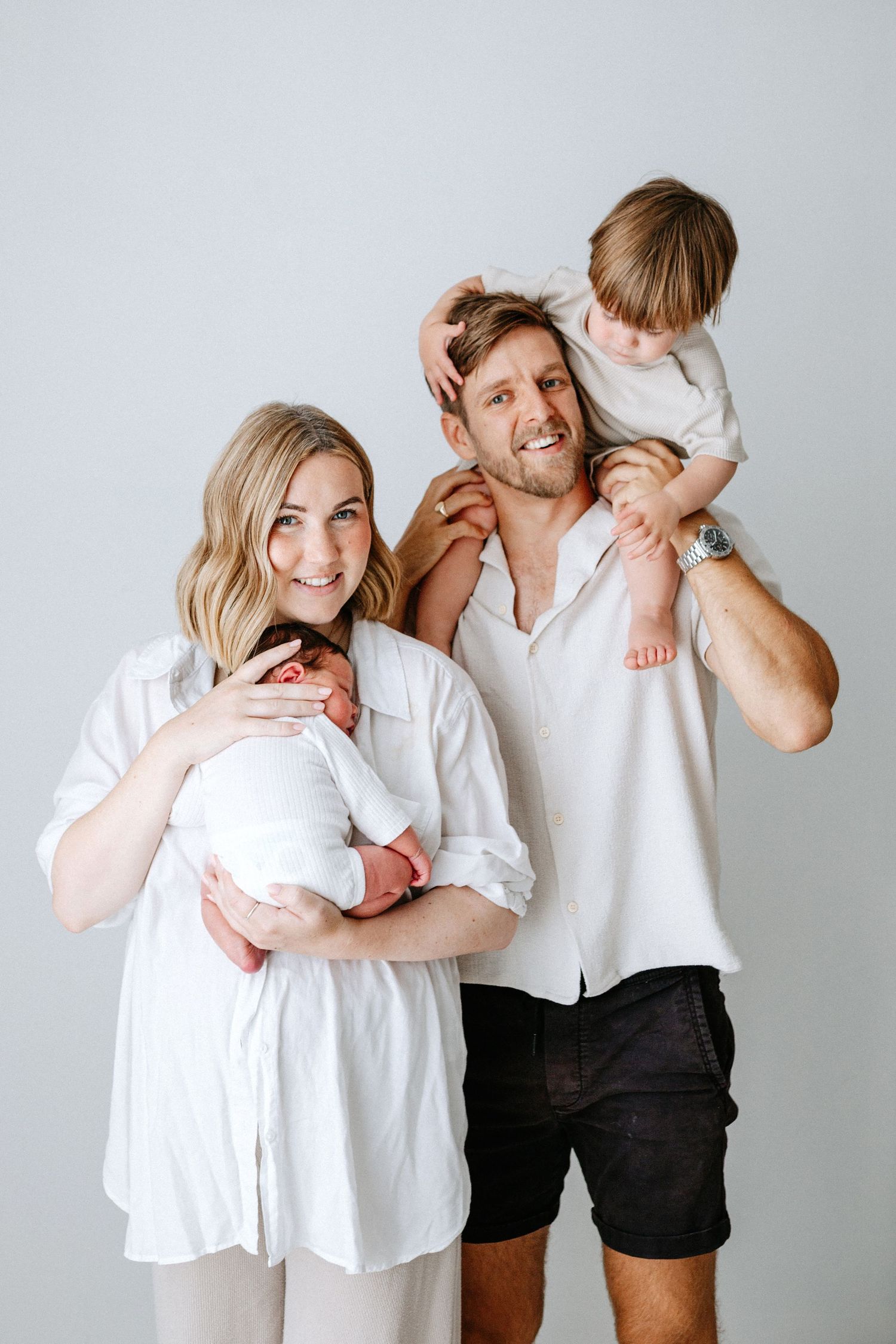 A loving couple in white and black clothing shares tender moments in a series of candid portrait shots against a light background.