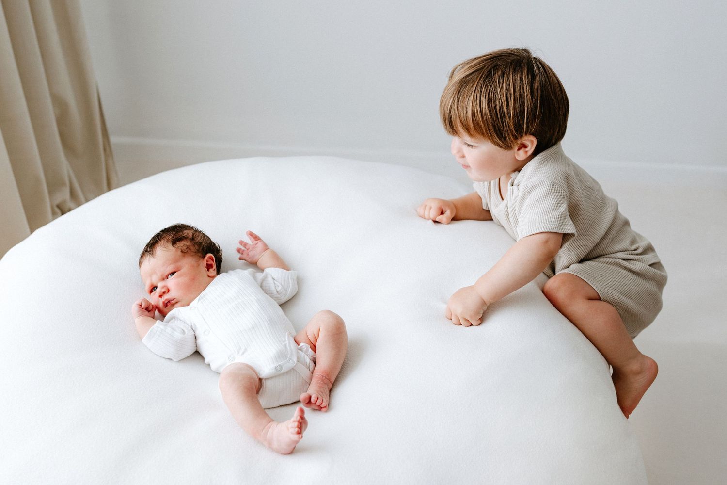 A photo series showing a baby rolling over on white bedding from left to right.
