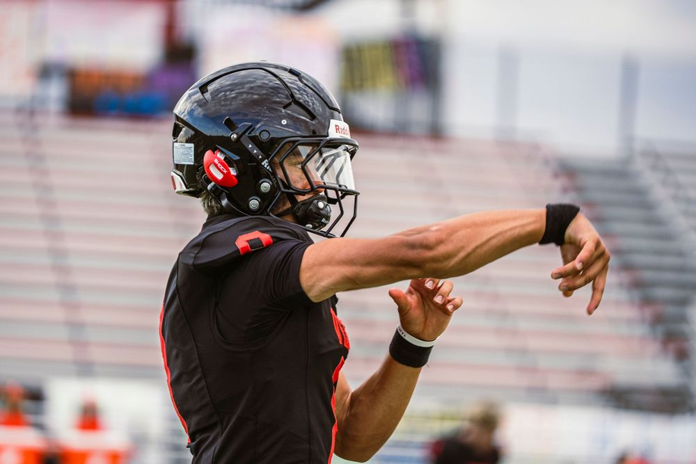 Football player after throwing a football off right frame