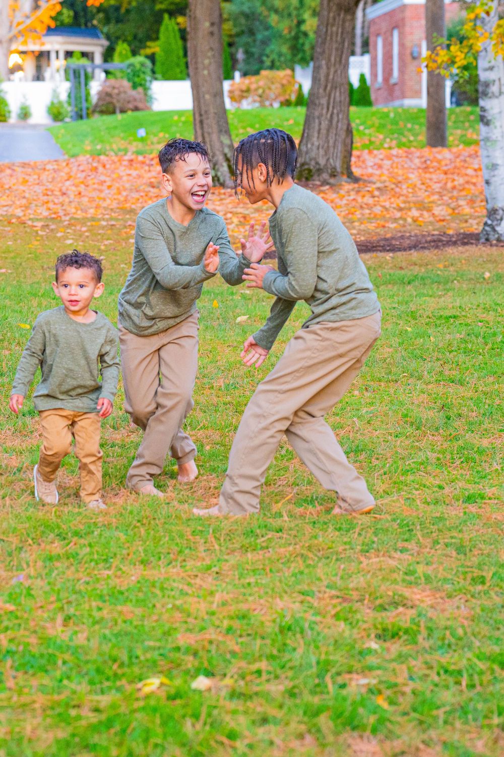 Children playing and running through fallen autumn leaves in park.