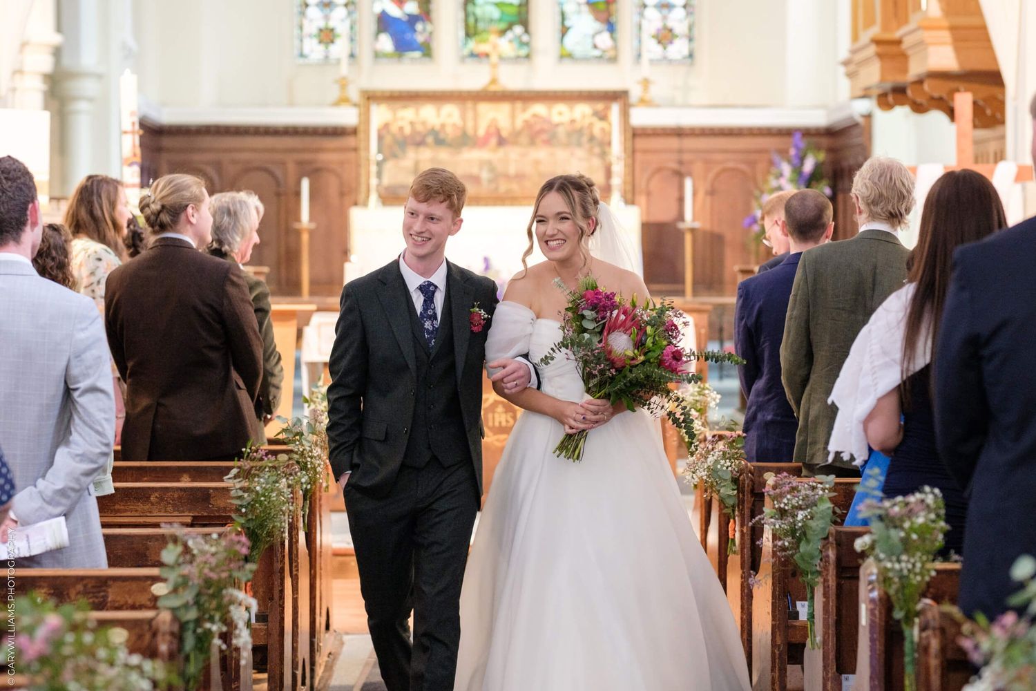 A couple walks down the church aisle together among guests during a traditional wedding ceremony.