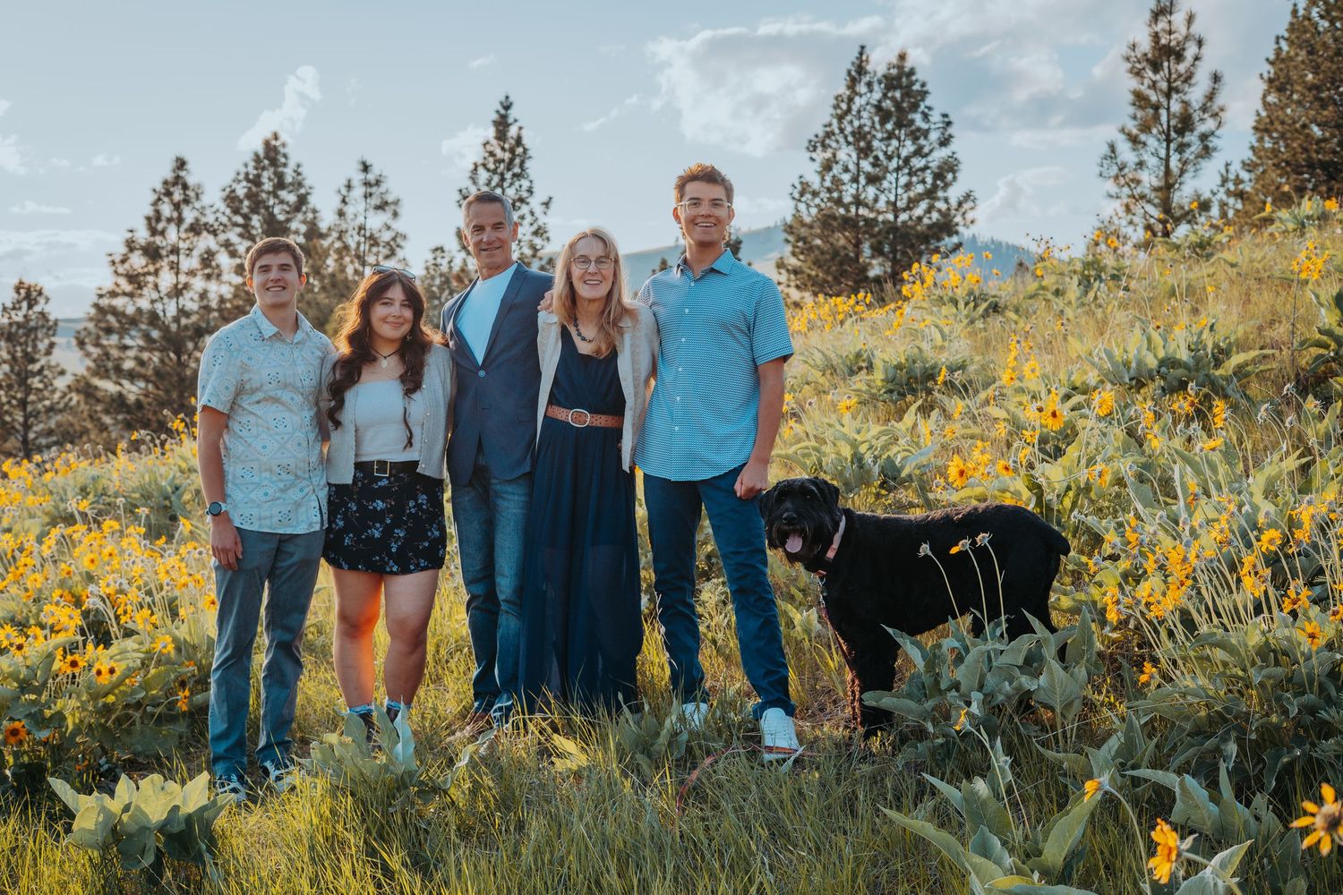 A group stands together in a scenic meadow filled with yellow wildflowers during golden hour.