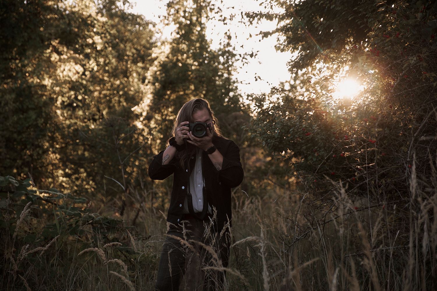 Silhouette of a photographer taking pictures during golden hour in tall grass.