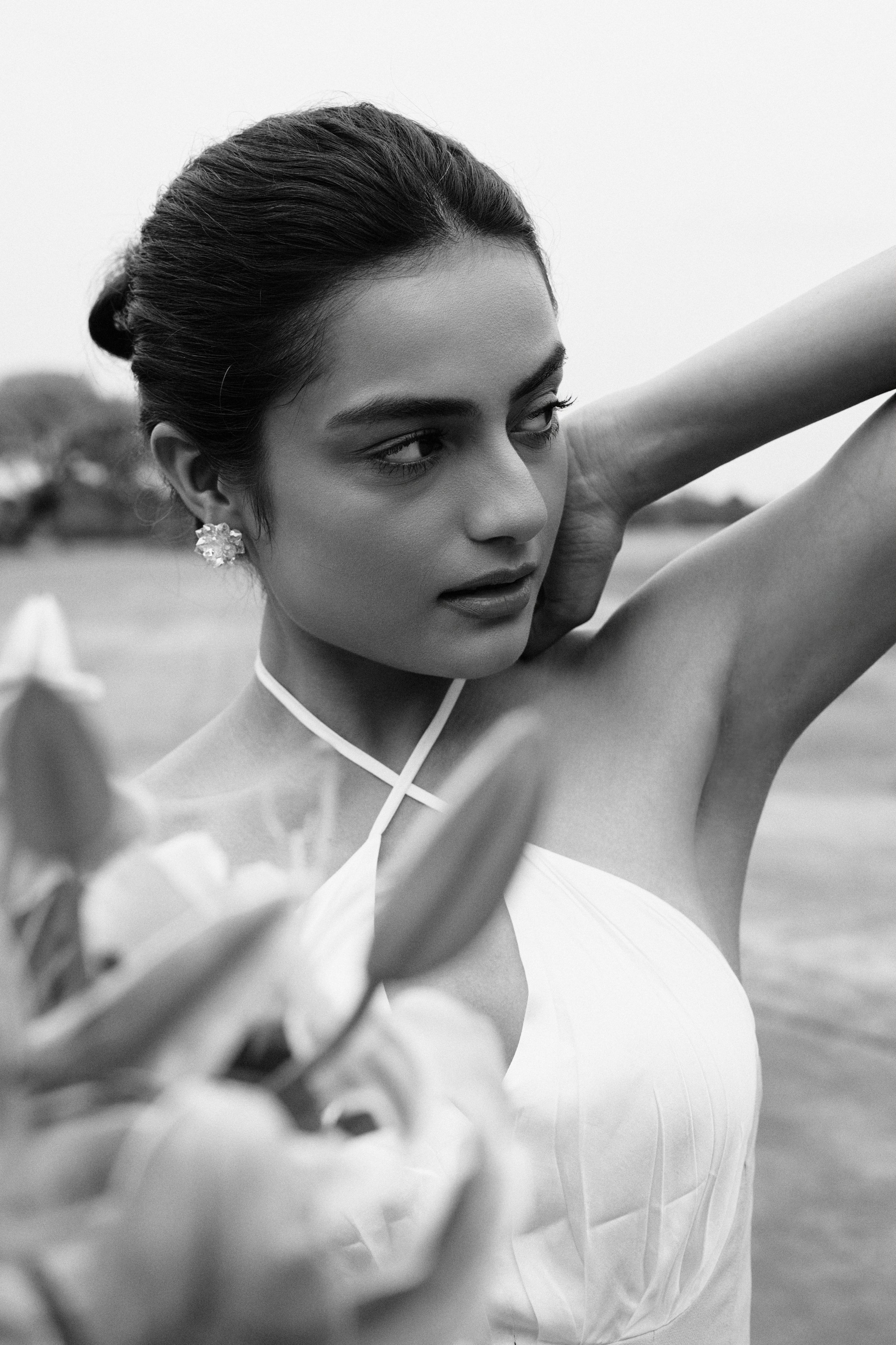 Black and white portrait of a model in a structured dress, captured with dramatic shadow and minimalist composition.