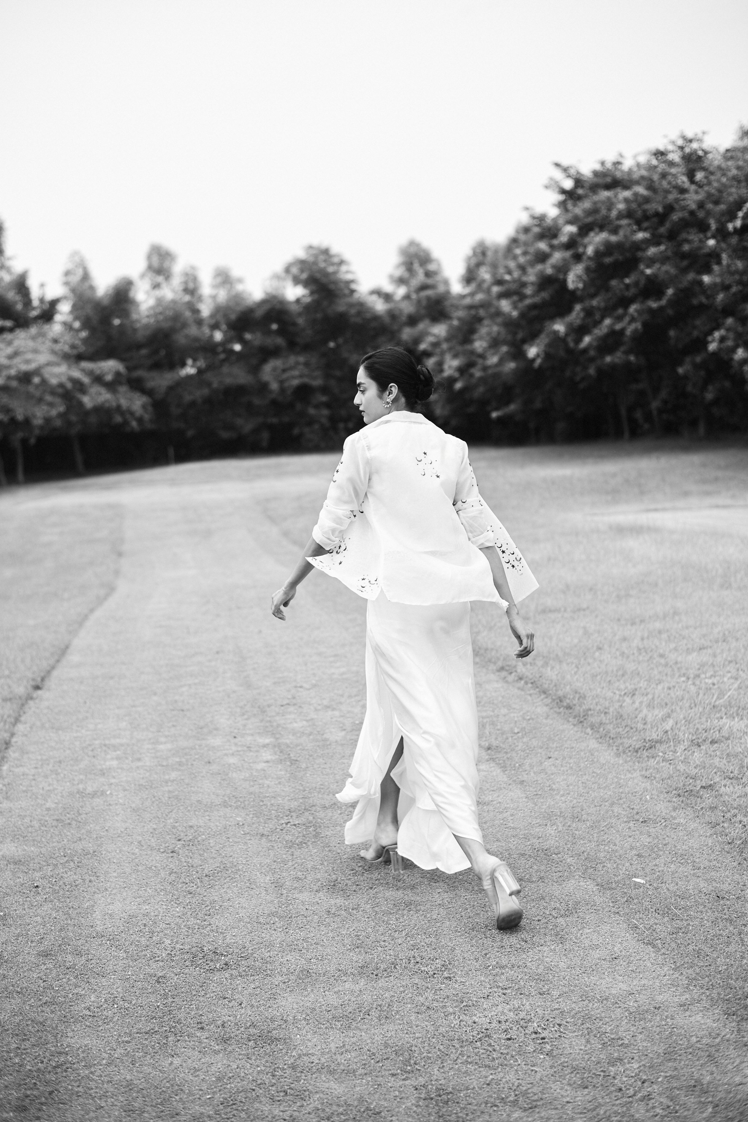 Fashion photograph of a model in an asymmetric dress, posture accentuating clean lines and fabric movement.