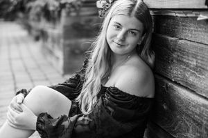 A black and white series of headshots showing various natural poses and expressions leaning against a wooden wall.