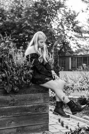Black and white artistic photo in a garden with raised wooden planters and lush greenery.
