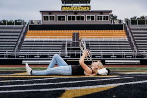 Black and white photo of student athletes posing on football stadium bleachers in dramatic lighting.