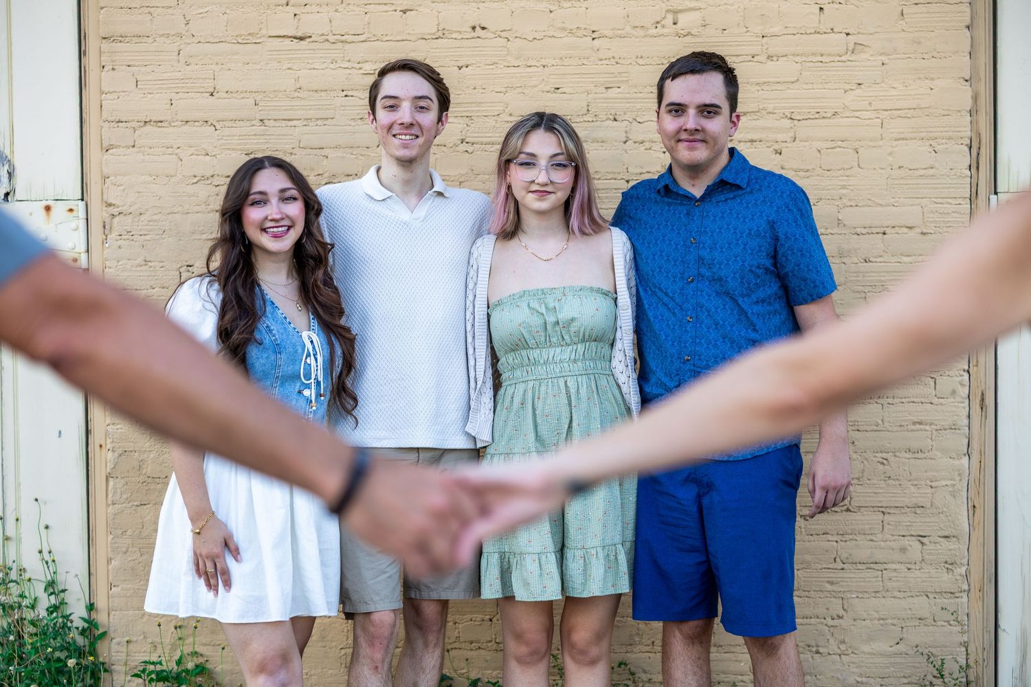 A group of people stand together outdoors wearing coordinated blue and white casual summer outfits for a photo.