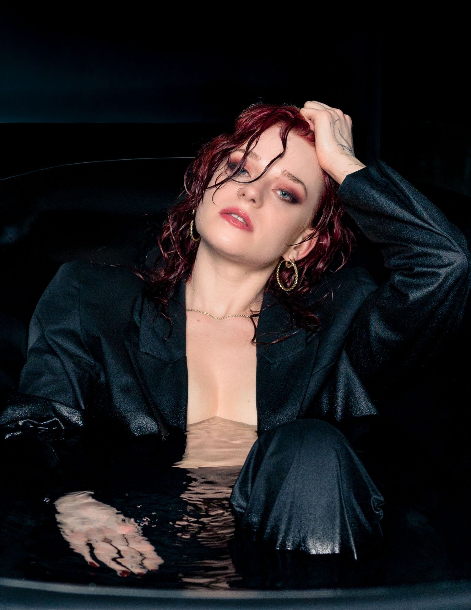 Editorial portrait of a model with curly red hair in a black leather jacket, dramatic low-key lighting, close-up variant