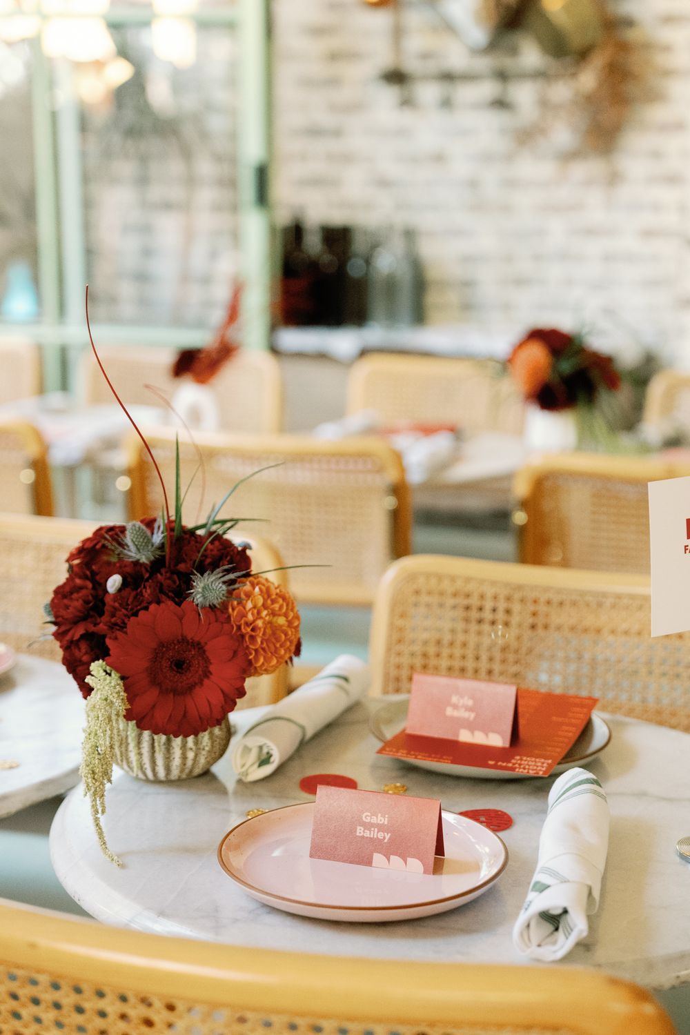 Elegant wedding reception table with red floral centerpiece and place cards on marble table.