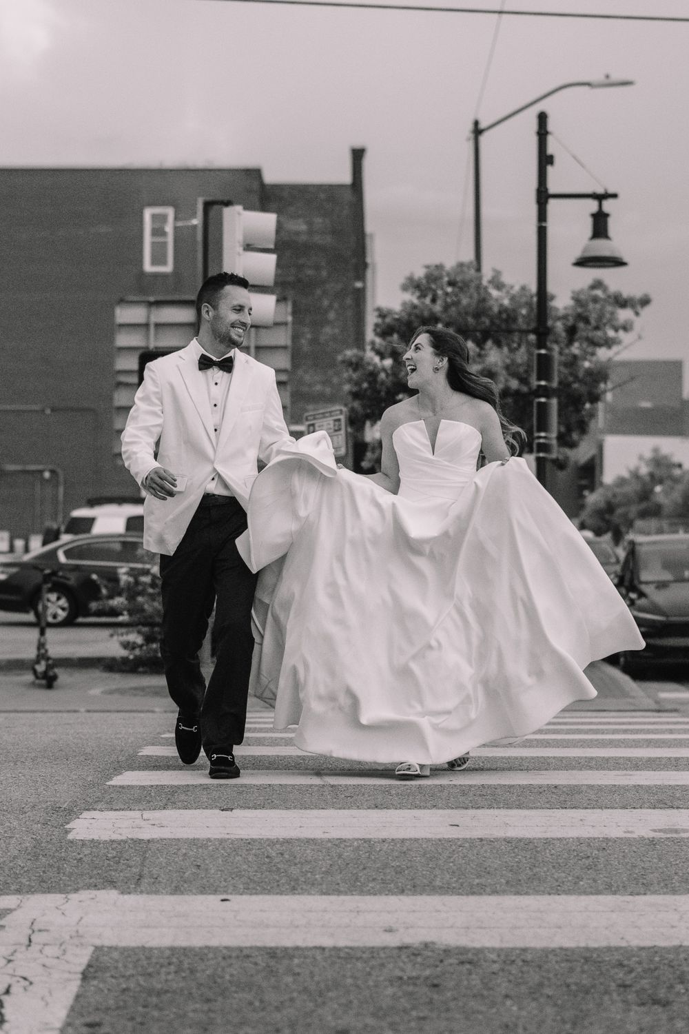 Black and white sequence of a couple in formal attire posing on a street with flowing white dress fabric.