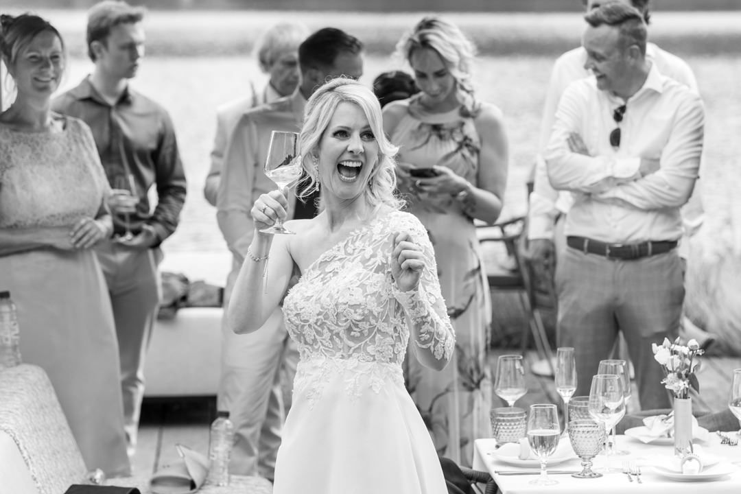 Bruid heft een champagneglas tijdens de receptie na de ceremonie bij L Seven