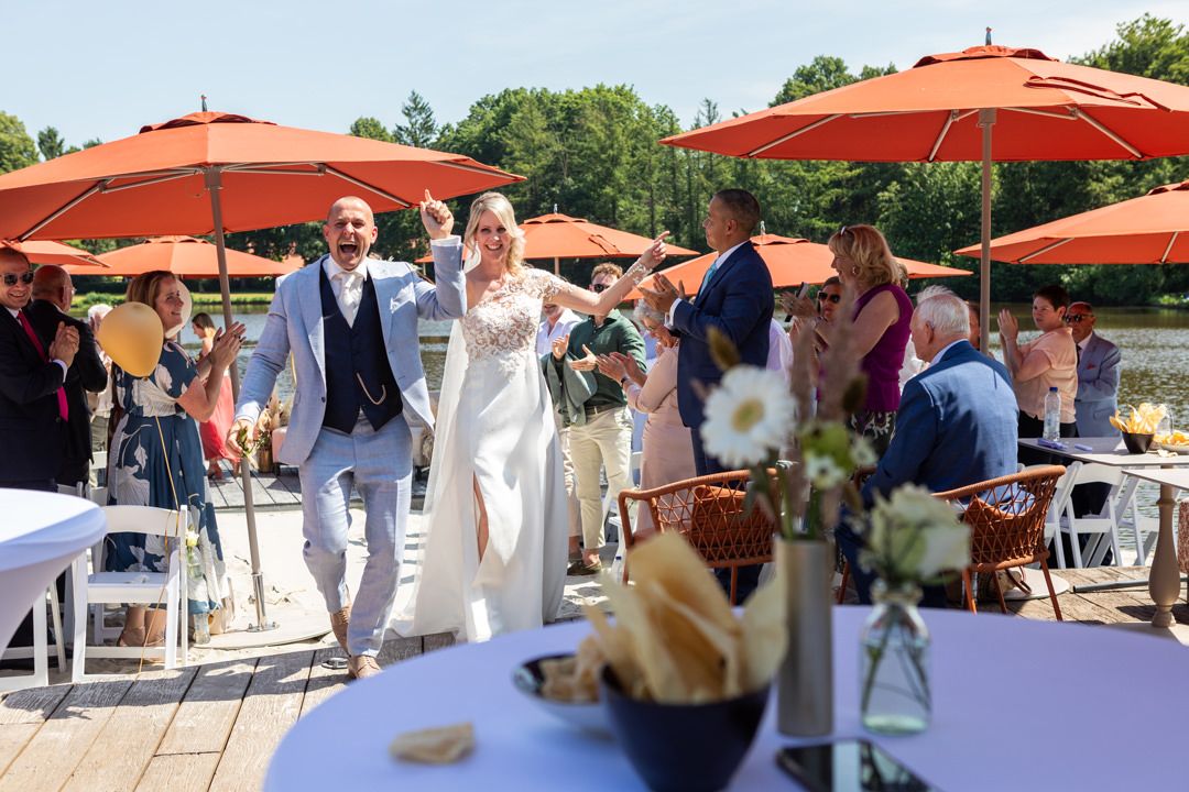 Bruidspaar loopt langs de gasten na afloop van de ceremonie bij L Seven