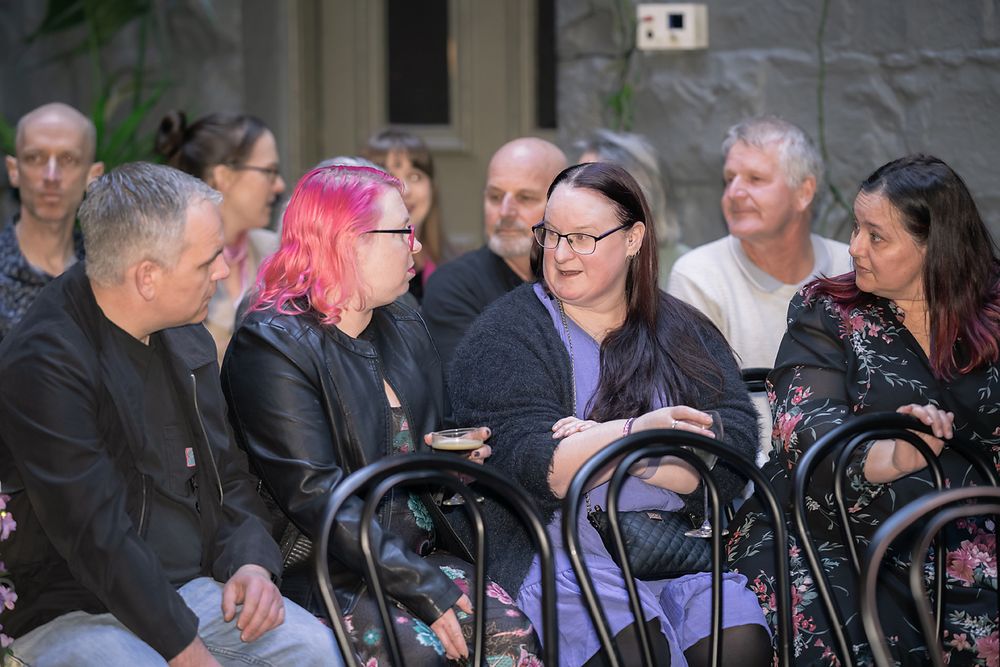 Group of people seated in a casual outdoor setting having conversation together.