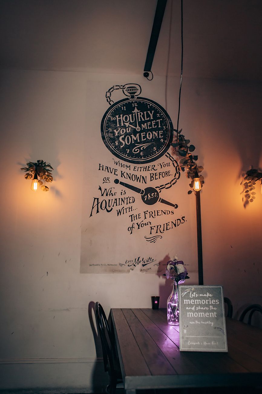 Artistic wall decor with stylized text and decorative lighting elements in a dimly lit ambiance creates a cozy atmosphere.