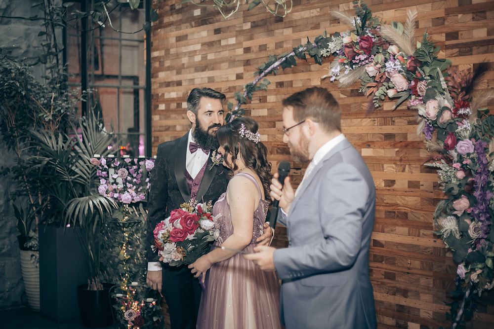 Wedding couple shares romantic moments together at rustic venue with wood walls and floral decorations.