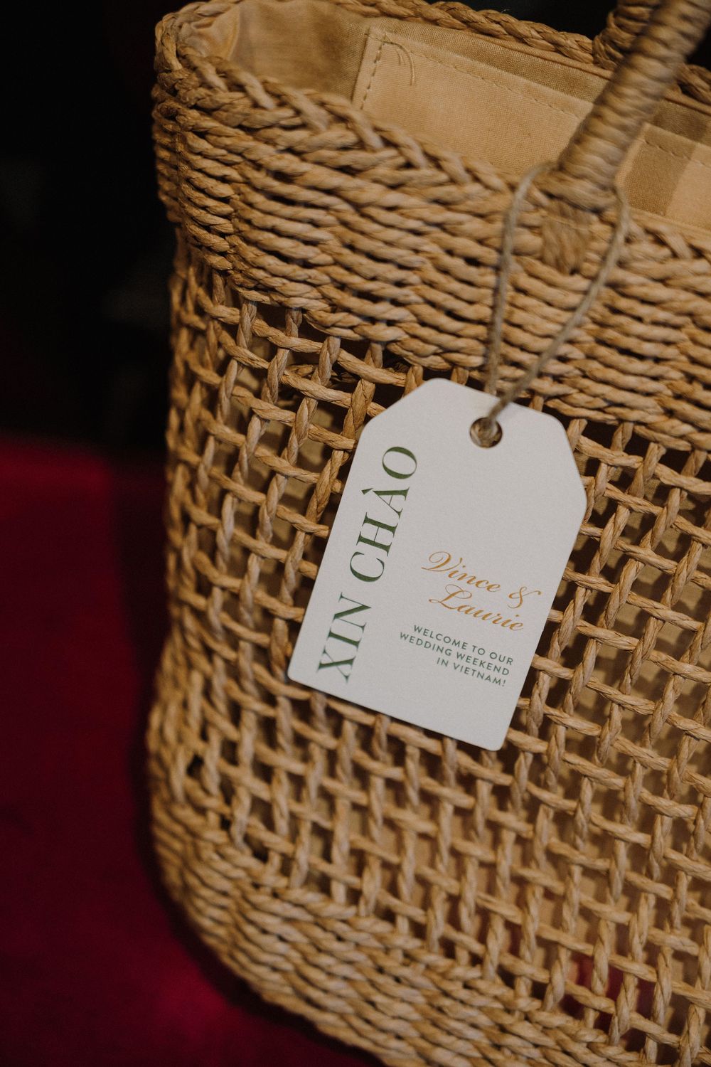 Close-up detail showing beige woven basket with white gift tag against dark background.