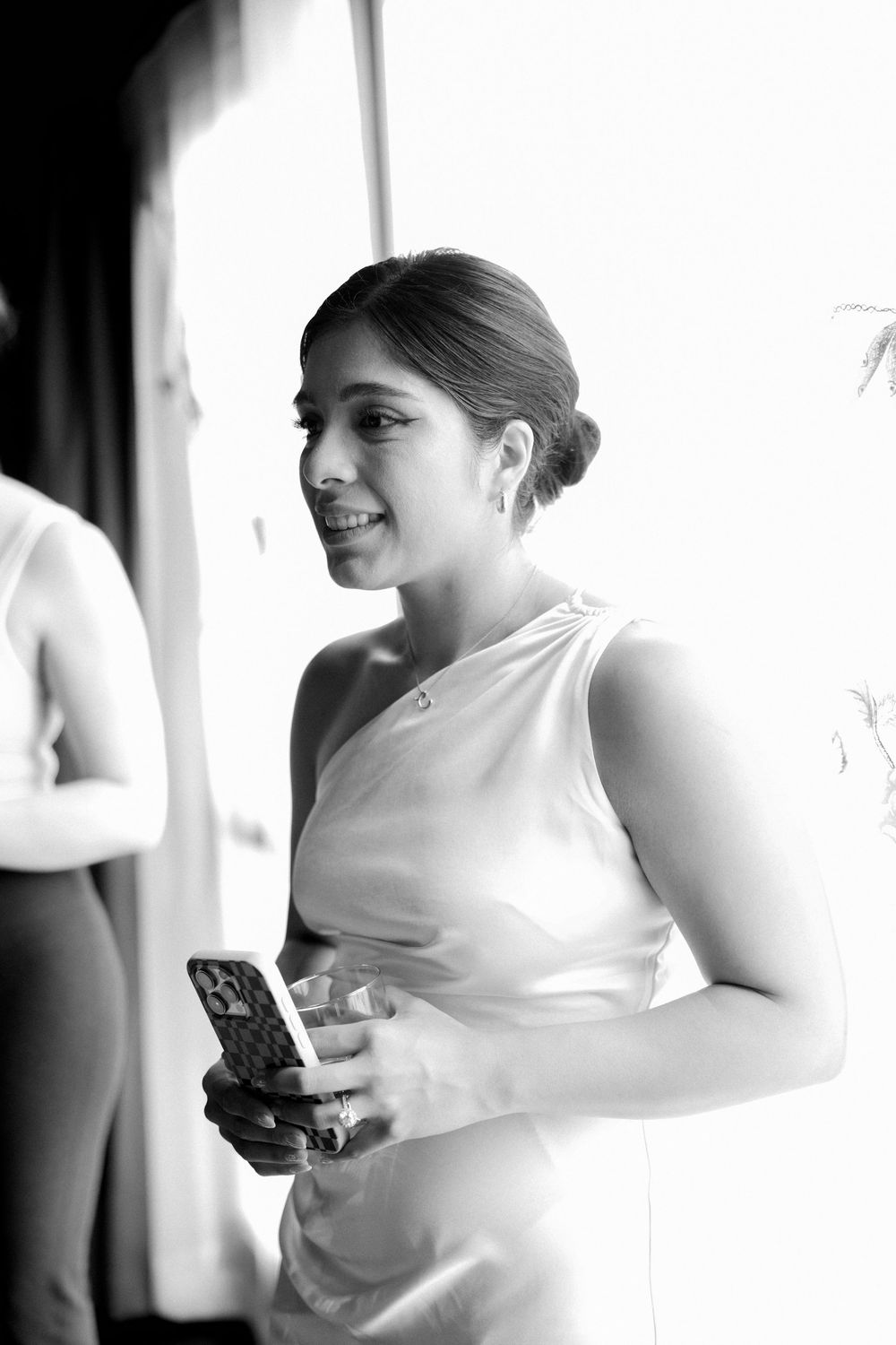A series of black and white photos showing someone wearing white, sitting and holding a mobile phone in different poses.