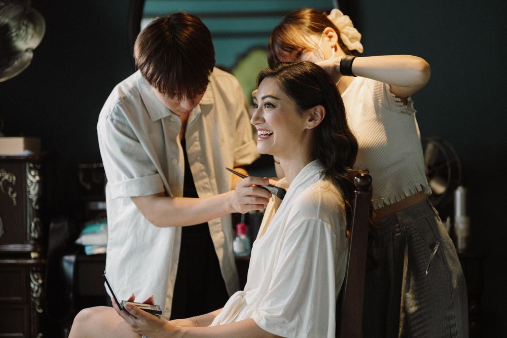 Makeup artist applies eyeshadow on client during professional beauty session in studio setting.