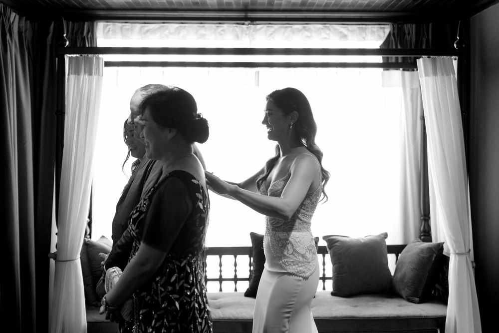 Wedding preparations in black and white as a bride gets ready with bridesmaids in a sunlit room.