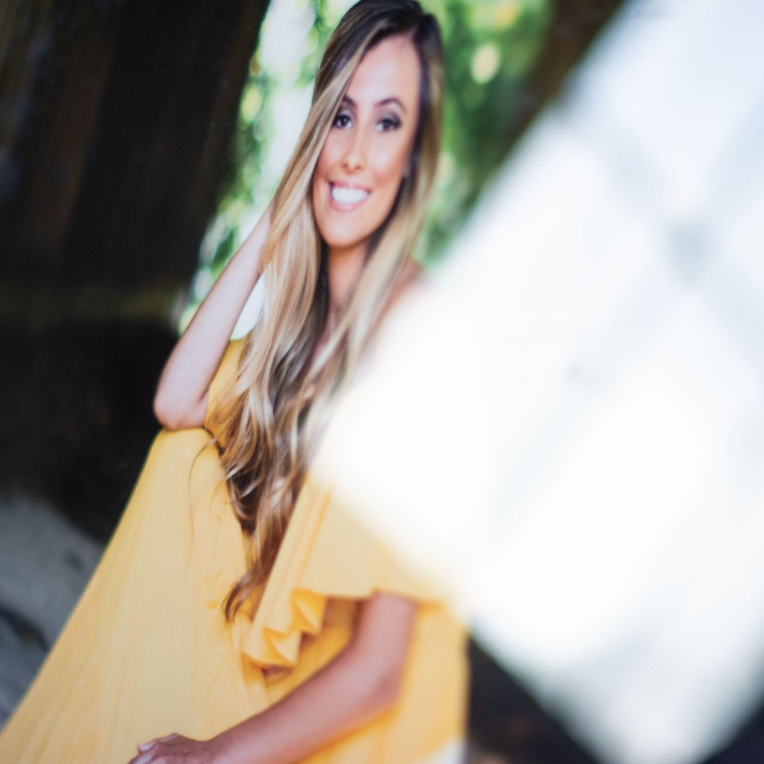 Portrait series in yellow dress against blurred natural background.