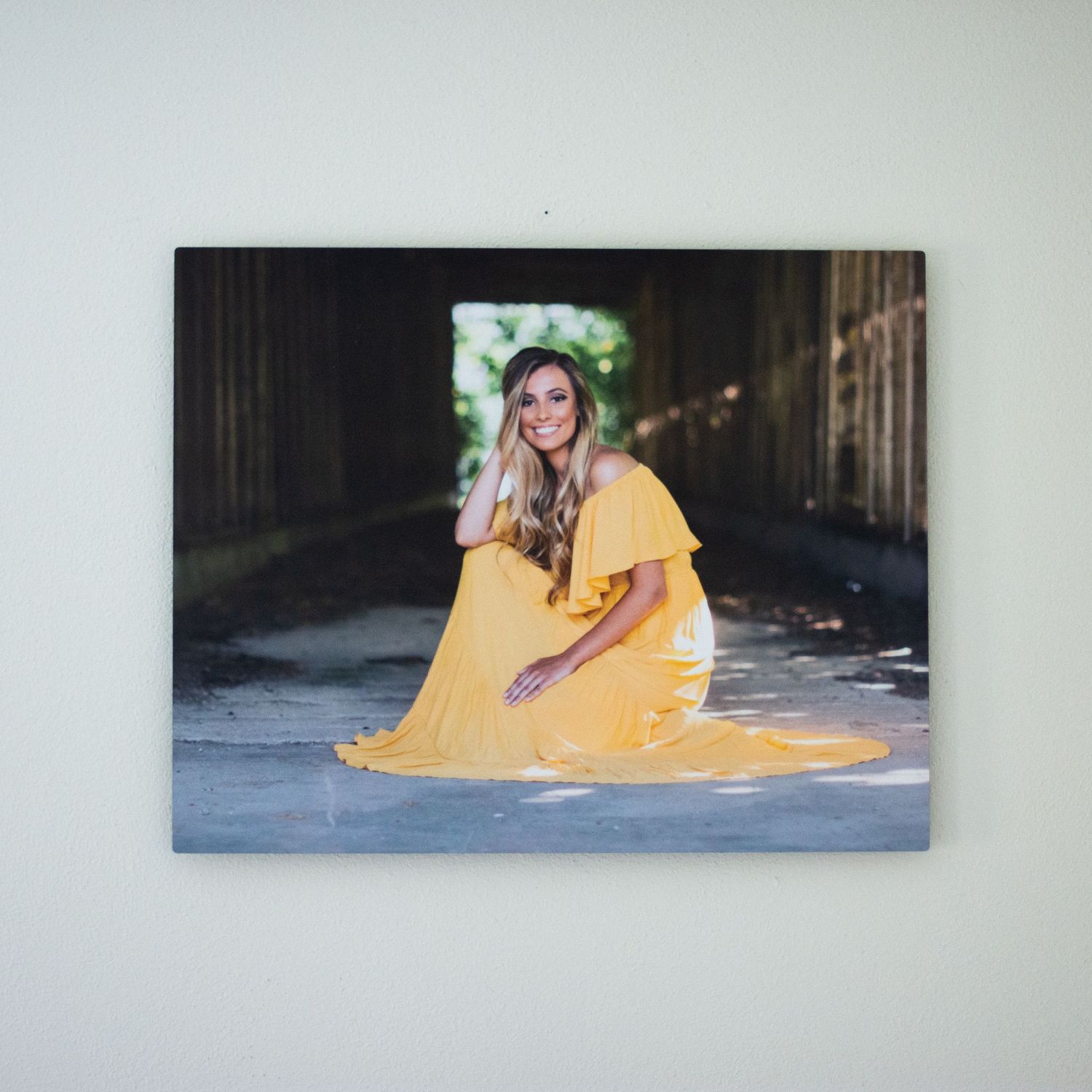 Gallery wall display of portrait photographs in yellow theme against white wall.