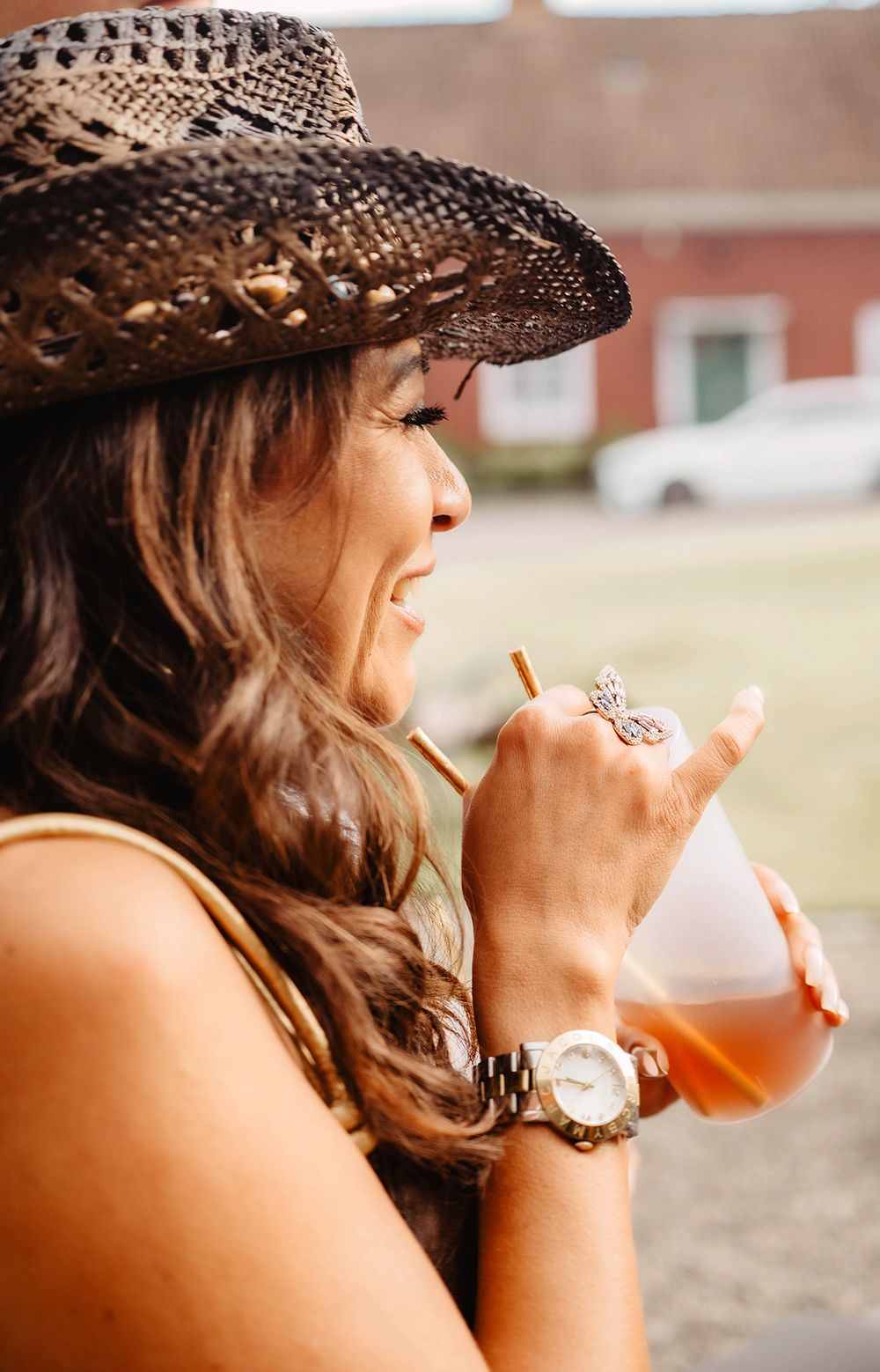 En kvinnlig gäst i cowboyhatt dricker en välkomstdrink under ett fest med cowboytema, Fotograf Lets Bloom Media i Finspång.