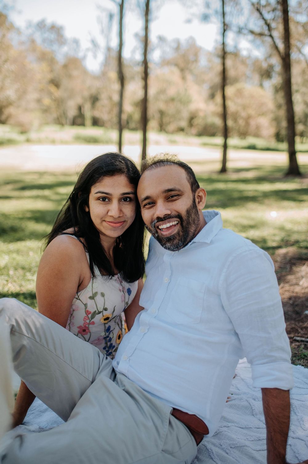 Series of intimate portraits showing a couple resting on white linens in a park setting.