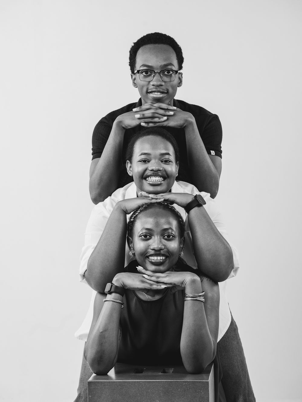Black and white photo series showing joyful playful poses and expressions against a plain backdrop.