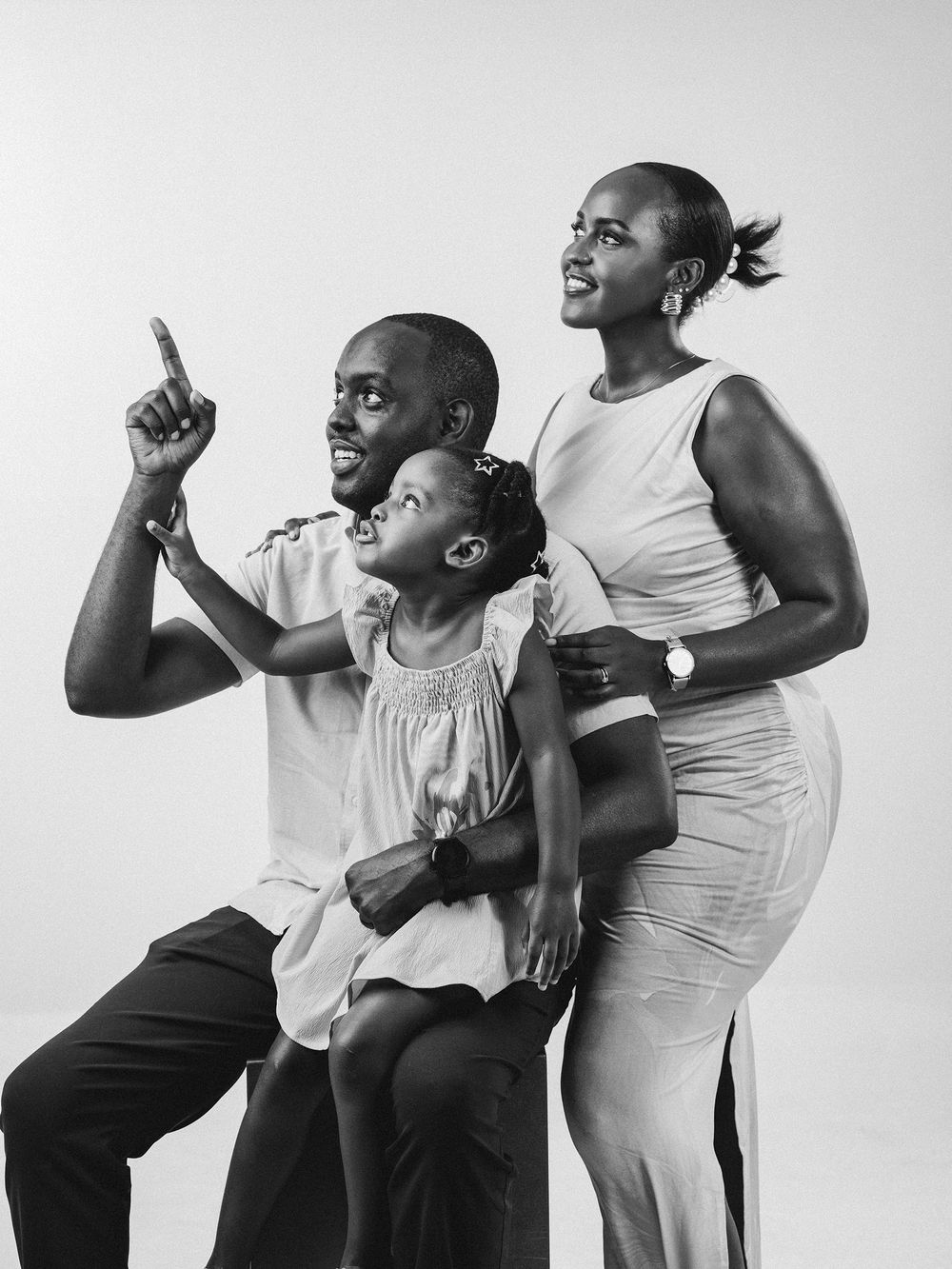 Black and white photo sequence showing playful family poses against white background, capturing joyful expressions and movement.