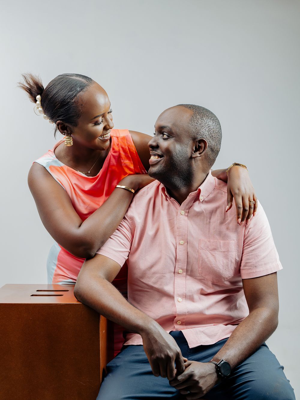 A couple sitting together and sharing an intimate moment in a warm peach and coral color scheme.