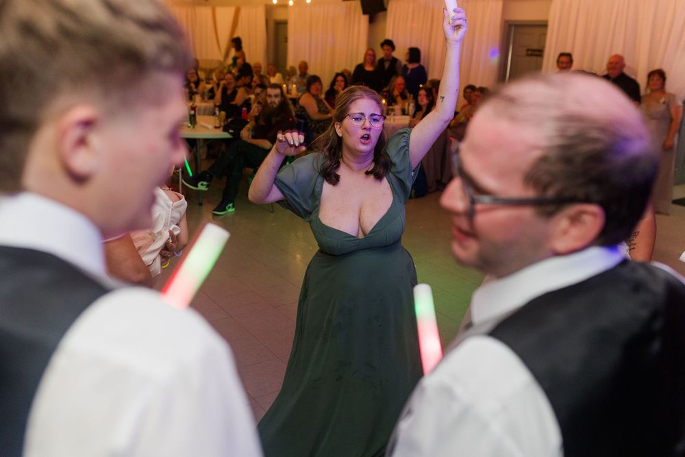 Wedding reception guests dancing and celebrating together on the dance floor under colorful party lights.