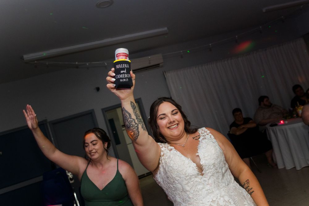 Two people dancing energetically at a party with one holding up a beverage in celebration.
