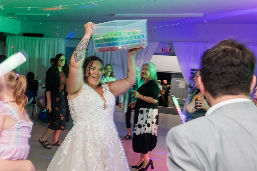 Dancing guests celebrate on a dance floor illuminated by blue and purple event lighting.