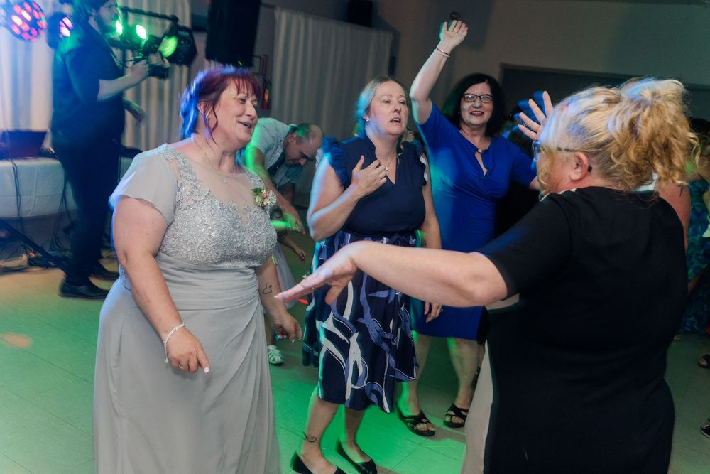 Partygoers dancing and celebrating on a dance floor with colorful lighting effects.
